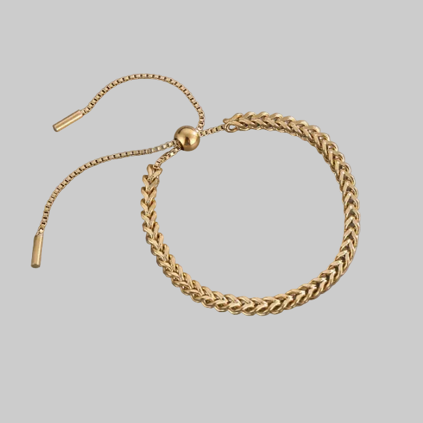 Gold chain bracelet on a grey background