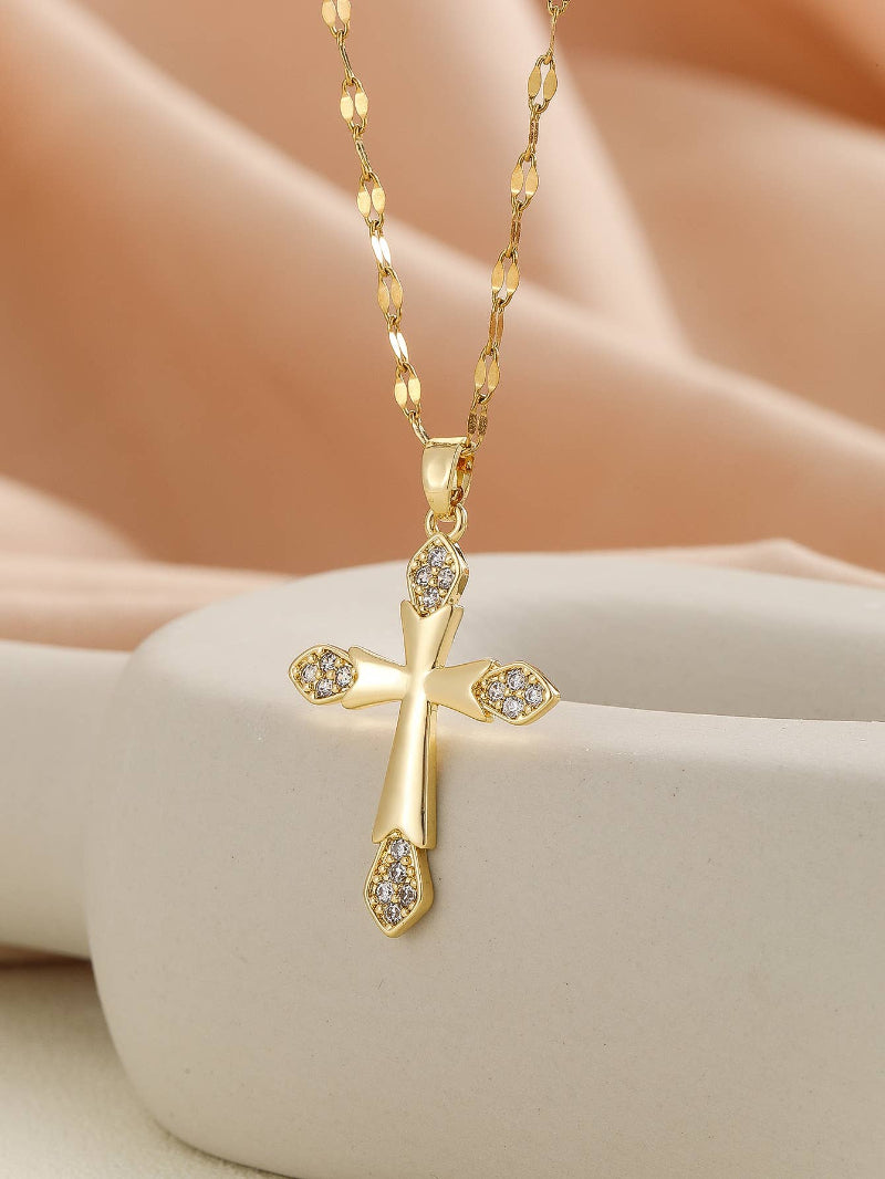 Gold cross necklace with diamonds on a beige surface