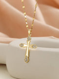 Gold cross necklace with diamonds on a beige surface