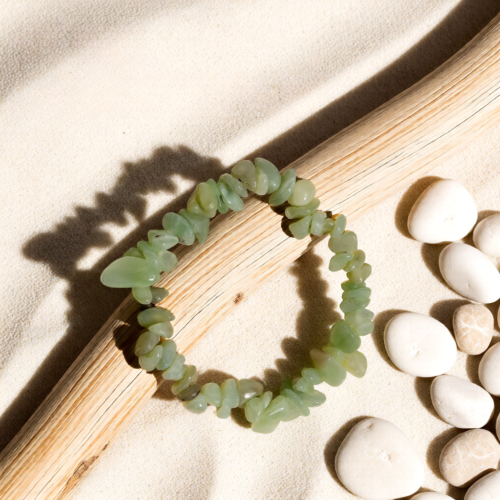 Green stone bracelet on a wooden surface with pebbles