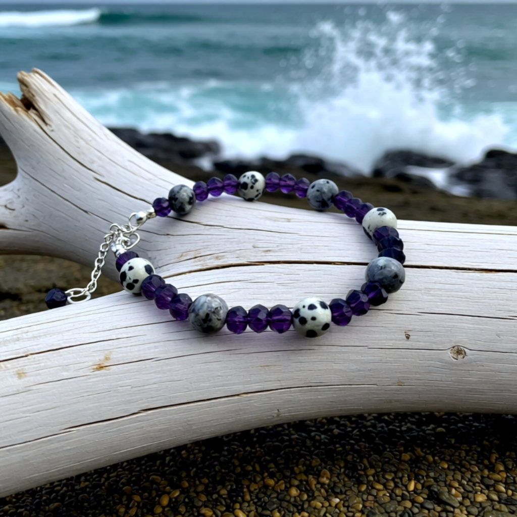 Beaded bracelet on a piece of driftwood with ocean waves in the background 