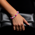 Hand wearing a colourful bracelet on a black clutch