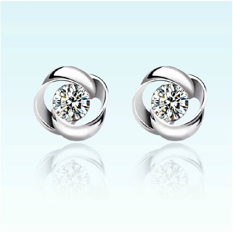 Pair of silver earrings with clear gemstones on a light blue background