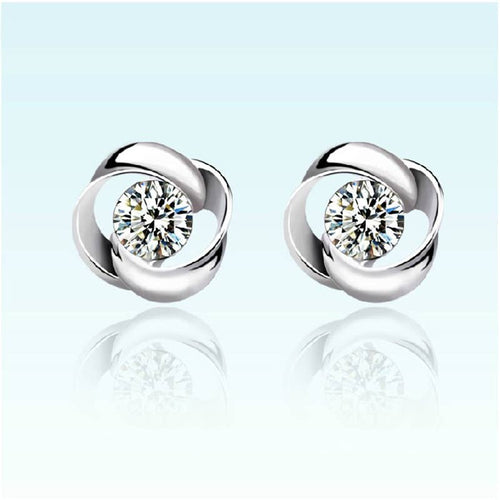 Pair of silver earrings with clear gemstones on a light blue background