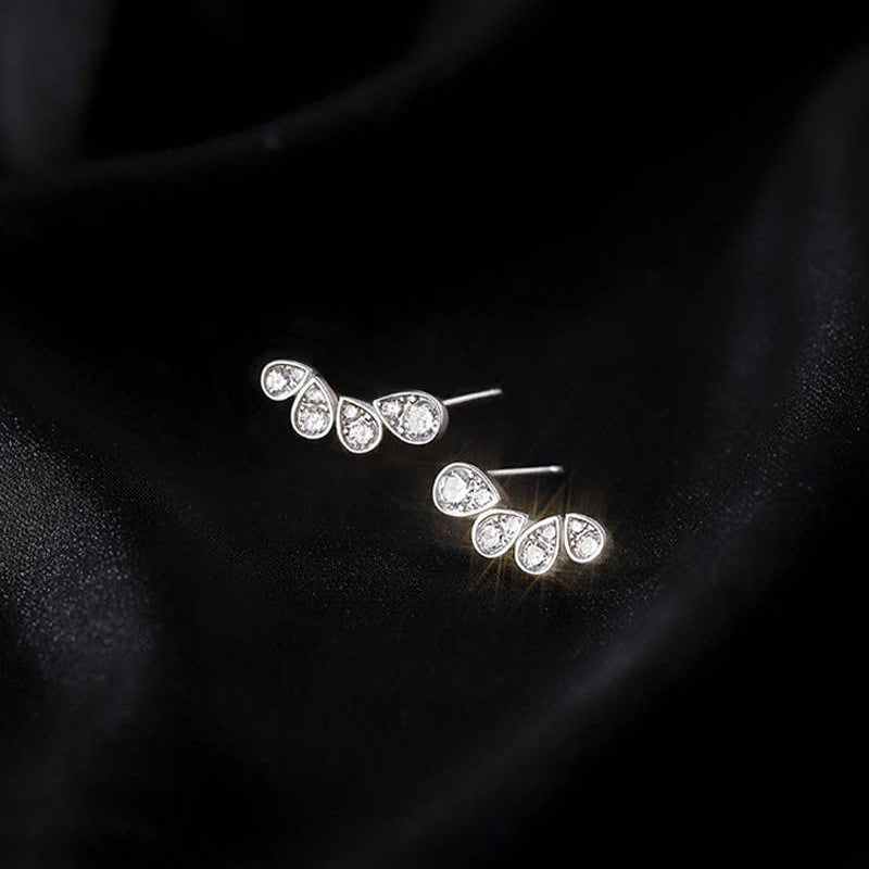 Pair of silver earrings with clear gemstones on a dark background