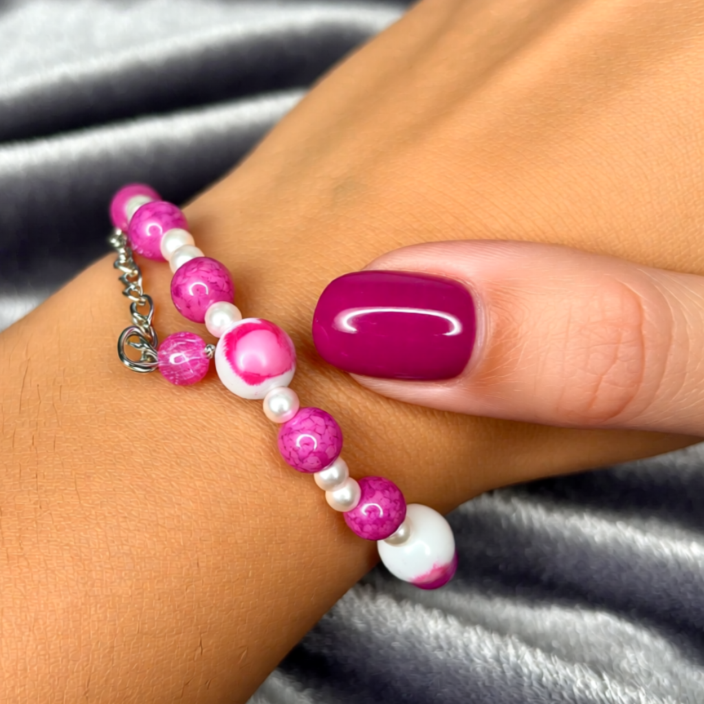Close-up of a wrist wearing a pink and white beaded bracelet with a blurred background.