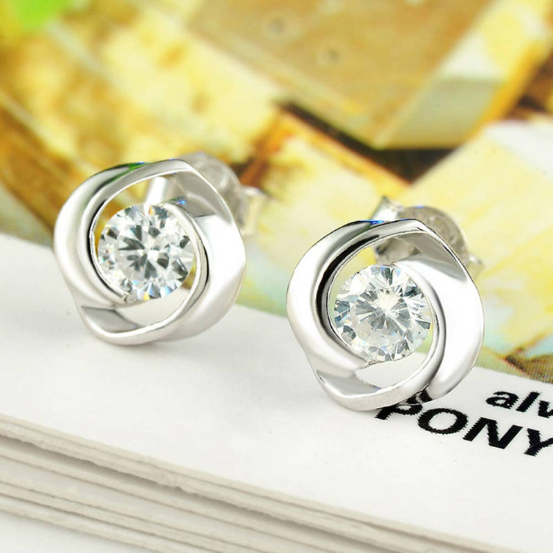 Silver earrings with clear gemstones on a magazine background
