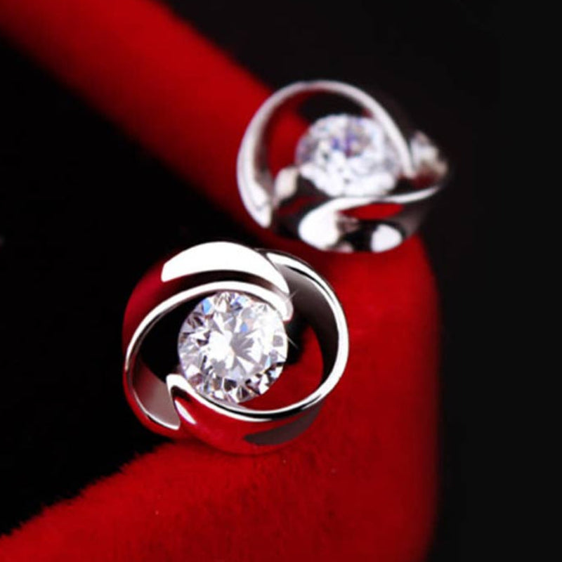 Silver earrings with clear gemstones on a red surface